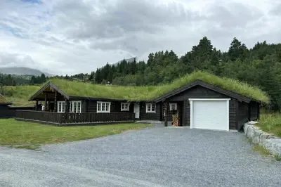 a house with a grass roof with a garage at Fjellhytte sentralt og solrikt in Stryn