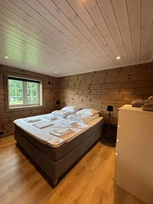 a large bed in a room with a wooden wall at Fjellhytte sentralt og solrikt in Stryn