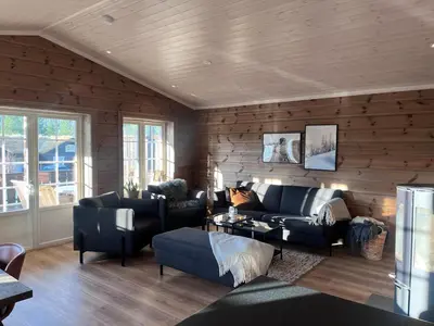 a living room filled with furniture and a wooden wall at Fjellhytte sentralt og solrikt in Stryn