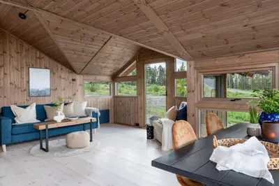 a living room with a blue couch and a table at Hedda Robølshøvda - 3 bedroom cabin with a lovely view in Heggenes
