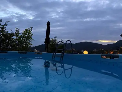 a large swimming pool with a umbrella and a chair at Home with 5 bedrooms, great view and garden in Bergen