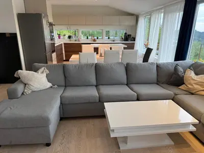 a living room with a gray couch and a kitchen at Home with 5 bedrooms, great view and garden in Bergen