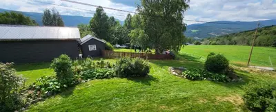a small house in a grassy field next to a building at Free EV Charging with Snacks and View in Blesom