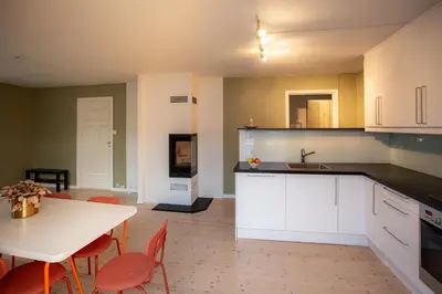 a kitchen with white cabinets and a table and chairs at Quiet place near city centre and the mountains in Bergen