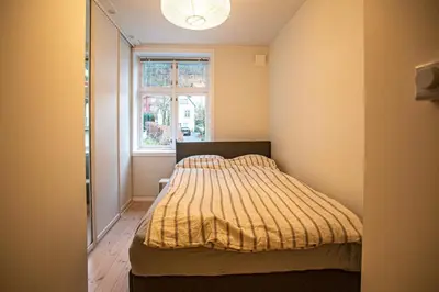 a bedroom with a bed with a yellow comforter and a window at Quiet place near city centre and the mountains in Bergen