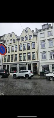 a white car parked in front of a large building at Ålesund Central Apartment in Ålesund