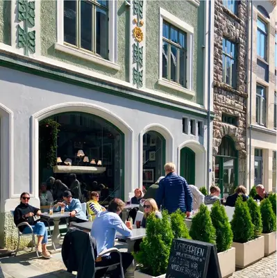 a group of people sitting at tables outside a building at Ålesund Central Apartment in Ålesund