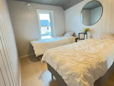 a bedroom with two beds and a mirror and a window at 6 person holiday home in Huglo in Nordhuglo