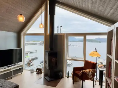 a living room with a fireplace and a large window at 6 person holiday home in Huglo in Nordhuglo