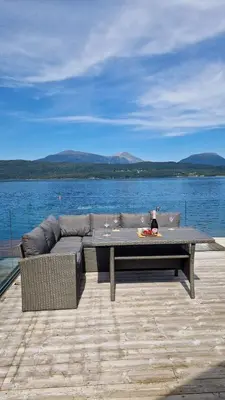 a couch and a table in front of a body of water at Seaside cabin with stunning view! in Ålesund