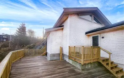 a house with a wooden deck next to a building at 3 Bedroom Awesome Home In Rossland in Rossland