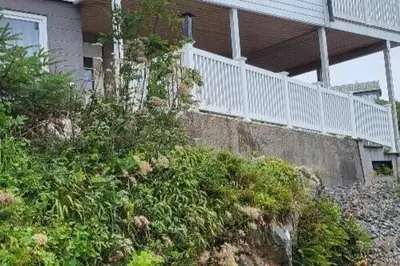 a house with a white railing on top of a hill at Cottage in Hellesøy, Øygarden in Hellesøy