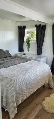 a bedroom with a bed and a window with black curtains at Cottage in Hellesøy, Øygarden in Hellesøy