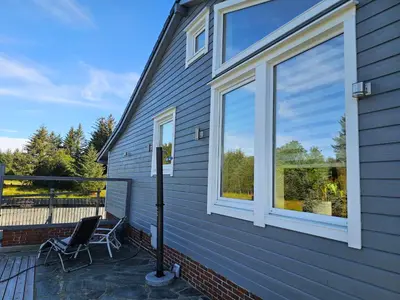 a patio with two chairs and a window on a house at Garsoniera in Leirvåg