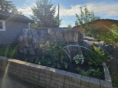 a rock garden with a waterfall in front of a house at Garsoniera in Leirvåg