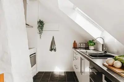 a white kitchen with a sink and a staircase at Leilighet Bergen Sandviken in Bergen