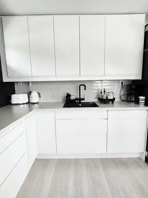 a white kitchen with white cabinets and a sink at Sentrumsidyll ved fjord og fjell in Molde