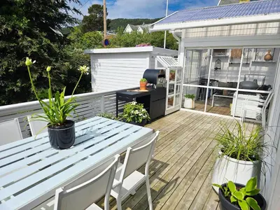 a patio with a table and chairs on a deck at Sentrumsidyll ved fjord og fjell in Molde