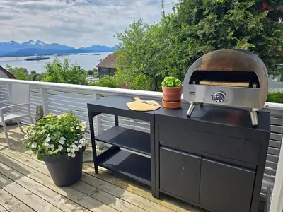 a grill on a deck with a view of the water at Sentrumsidyll ved fjord og fjell in Molde