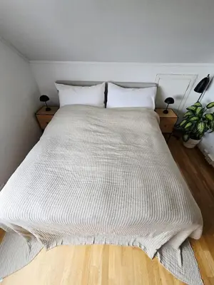 a bed with a white blanket on top of it at Sentrumsidyll ved fjord og fjell in Molde