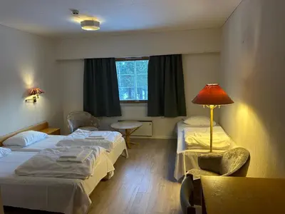 a room with two beds and a table and a lamp at Bjorliheimen Fjellhotell-Hotellrom in Bjorli