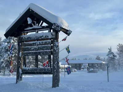 a snow covered building with flags in the snow at Bjorliheimen Fjellhotell-Hotellrom in Bjorli
