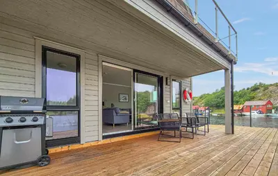 a deck with a stove and chairs on a house at Amazing Home In Bremnes With Wifi in Bremnes