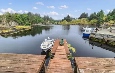 a boat is docked at a dock on a river at Amazing Home In Bremnes With Wifi in Bremnes