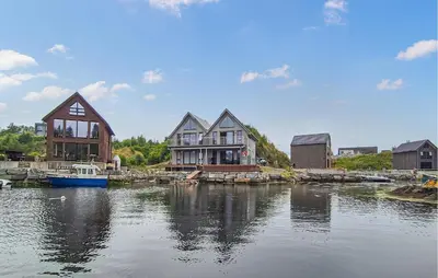 a group of houses on the water with a boat at Amazing Home In Bremnes With Wifi in Bremnes