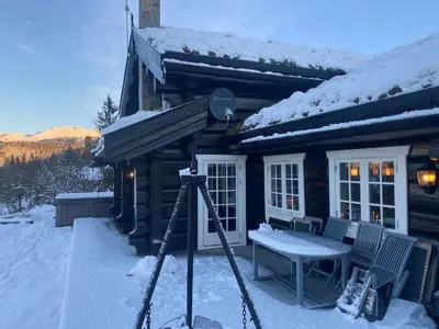 a camera in front of a log cabin in the snow at Stor velutstyrt laftehytte med usjenert uteplass, flott utsikt og Jacuzzi in Eggedal