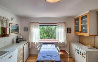 a kitchen with a table and a large window at Lovely Home In Masfjordnes With Wifi in Masfjorden