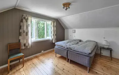 a bedroom with a bed and a chair and a window at Lovely Home In Masfjordnes With Wifi in Masfjorden