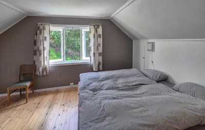 a bedroom with a bed and a chair and a window at Lovely Home In Masfjordnes With Wifi in Masfjorden