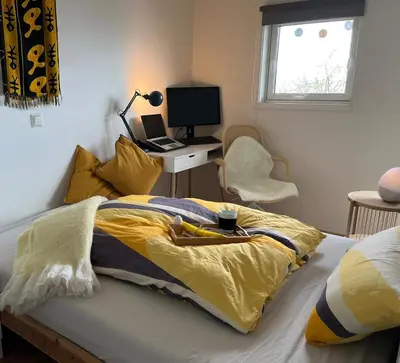 a bedroom with a bed and a desk with a laptop at Exclusive flat with amazing view over the fjord in Trondheim