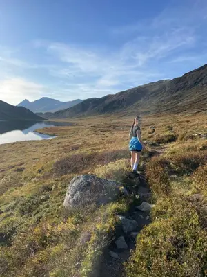 a woman walking down a trail on a hill at Stor tømmerhytte med fjellutsikt in Beitostøl