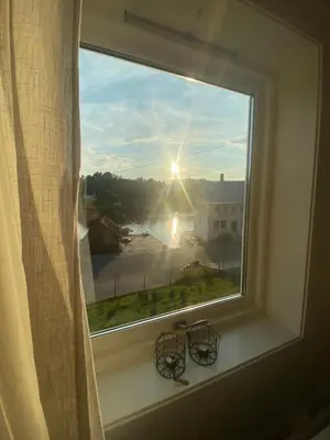 a window with a view of the sun shining through it at Haraldseidvågen gjestgjevarstad in Skjold