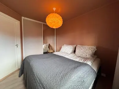 a bedroom with a bed and a chandelier at Modern apartment, large terrace free parking and Wallbox in Ytterland