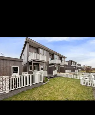 a large house with a white fence and a yard at Modern apartment, large terrace free parking and Wallbox in Ytterland