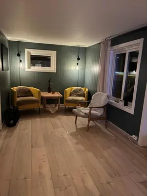 a living room with two chairs and a table at Flott feriehus ved sjøen
