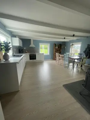a kitchen and living room with a table and chairs at Flott feriehus ved sjøen