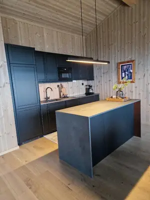 a kitchen with black cabinets and a island in a room at Ny hytte med panoramautsikt in Hjartdal