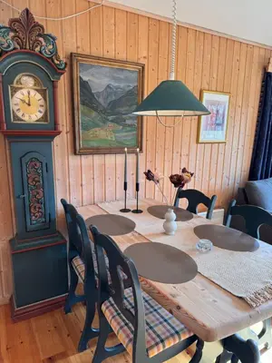 a dining room with a table and a grandfather clock at Høvringen Lodge in Høvringen