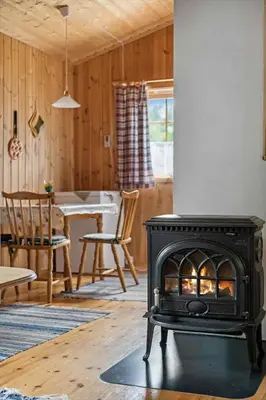 a stove in a living room with a dining room at Det er en fantastisk og romslig hytte i Slemdalen, Nordre Osen! in Åmot
