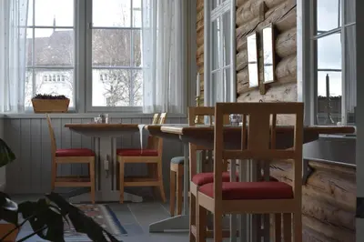 a restaurant with wooden tables and chairs and windows at Steien Hotel in Alvdal