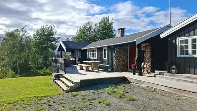a house with a patio with a table and benches at Trivelig hytte med innlagt strøm og vann Perfekt for familietur Bilveg helt frem in Rotvolden