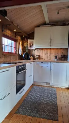 a kitchen with white appliances and a wooden ceiling at Trivelig hytte med innlagt strøm og vann Perfekt for familietur Bilveg helt frem in Rotvolden