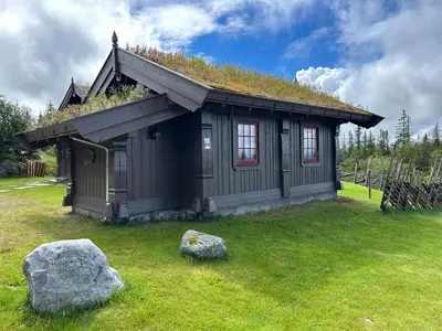 a small house with a grass roof with a rock at Sleepover in the mountains in Hjartdal