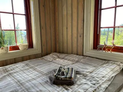 a bed in a room with two windows at Sleepover in the mountains in Hjartdal