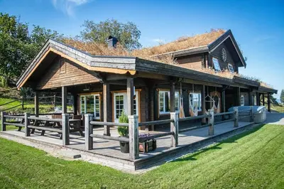 a large wooden house with a roof at Snerting Ranch Hotel - Comfty and modern Log House in Stokkan