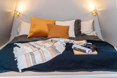 a bed with a remote control on top of it at Two bedroom penthouse with large living room and rooftop in the city centre of Trondheim in Trondheim